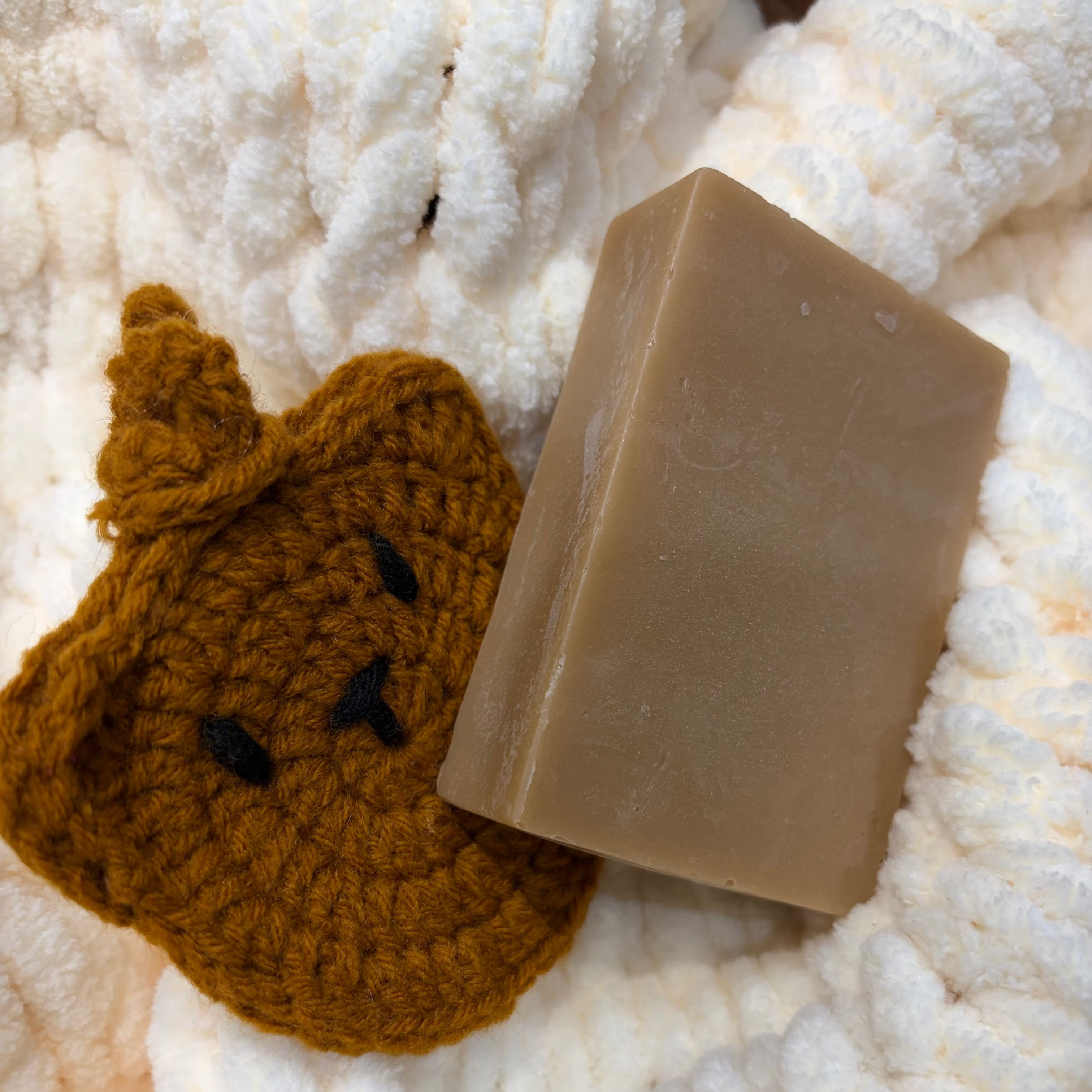 Bar of soap and brown crocheted bunny on a textured white surface
