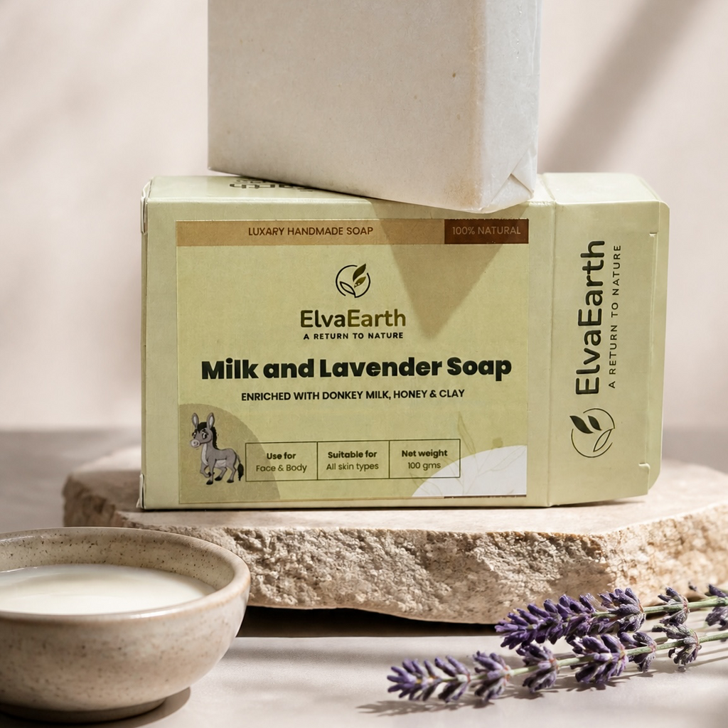A bar of ElvaEarth Milk and Lavender Soap stacked on its branded cream-colored packaging box, styled on a stone slab with a small bowl of soap and lavender sprigs in a warm, sunlit setting.