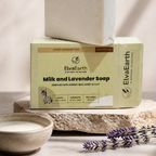 A bar of ElvaEarth Milk and Lavender Soap stacked on its branded cream-colored packaging box, styled on a stone slab with a small bowl of soap and lavender sprigs in a warm, sunlit setting.