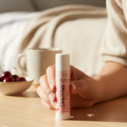 Person holding a skincare product on a wooden surface with a blurred background